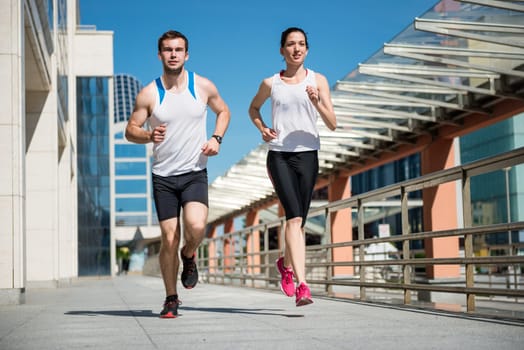Young sport couple jogging together in city environment