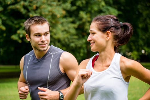 Young man and woman jogging outdoor and looking on each other