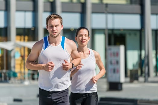 Young sport couple jogging in city environment - man first