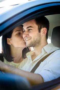 Couple in car - young woman kissing man in car while driving