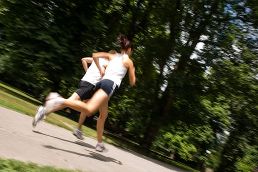 Young man and woman jogging outdoor in nature - motion blur image (panning)