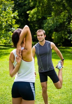 Young couple exercising and stretching muscles before sport activity - outdoor in nature