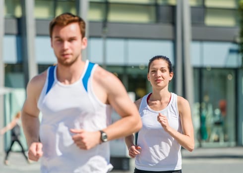 Young sport couple jogging in city environment - focus on woman