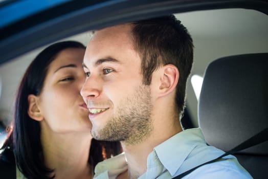 Couple in love - woman kissing man in car while driving
