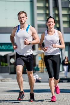 Young sport couple jogging together in city environment