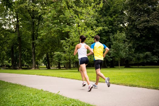 Fitness couple - young man and woman jogging in nature - rear view