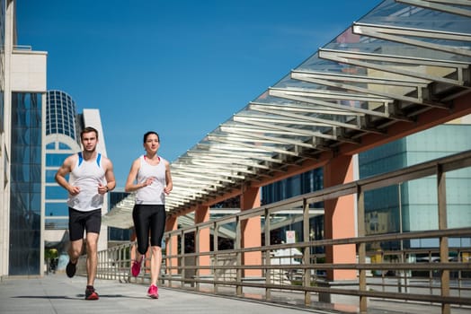 Young sport couple jogging together in city environment