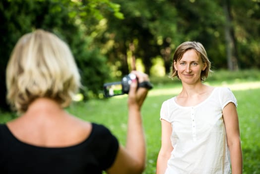 Senior woman is taking video of her adult daughter in nature