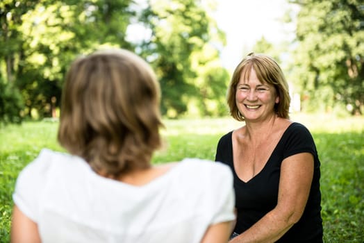 Senior woman chatting with her adult daughter outdoor in nature