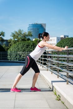 Young sport woman is stretching leg before jogging - outdoor in city