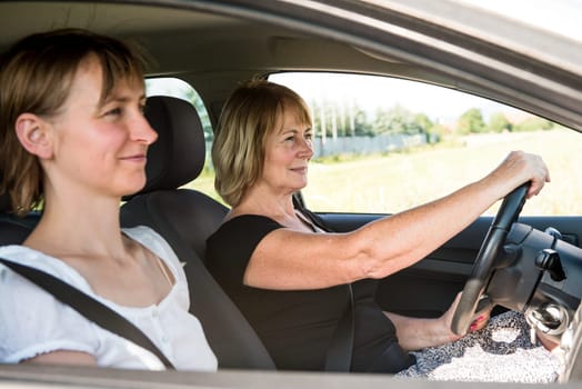 Smiling mature woman driving car with her adult child