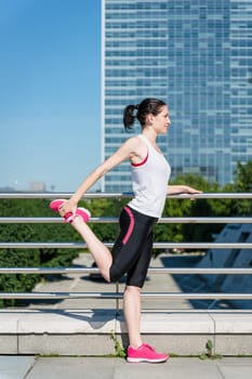 Young sport woman is stretching leg before jogging - outdoor in city