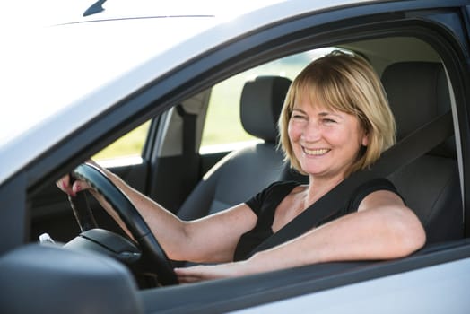 Lifestyle photo of attractive senior woman driving car