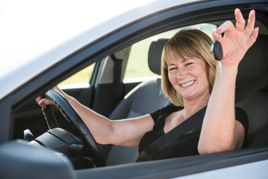 Portrait of attractive senior smiling woman holding keys from new car