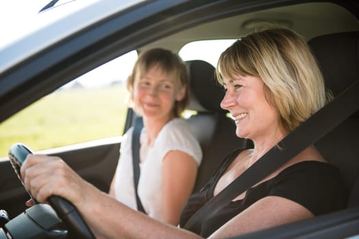 Smiling senior woman driving car with her adult child