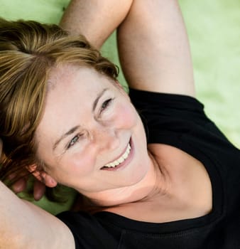 Smiling attractive senior woman lying outdoor on rug