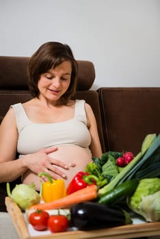 Lifestyle portrait of pregnant woman with vegetables in home kitchen