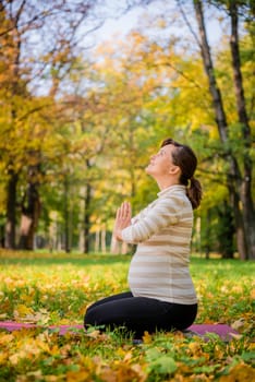 Happy pregnant woman giving thanks to god in autumn beautiful nature