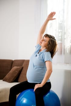 Pregnant woman exercising with fit ball at home