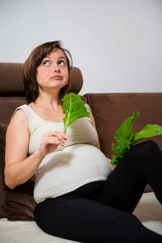 Lifestyle portrait of pregnant woman eating spinach at home
