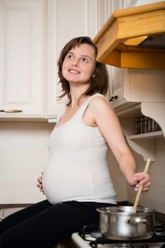 Lifestyle portrait of smiling pregnant woman cooking in home kitchen