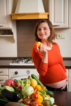 Pregnant woman with abundance of vegetables and fruits holding apple