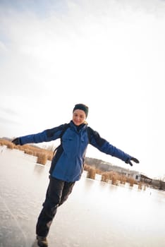 Young smiling woman is sliding on ice - winter outdoor scene