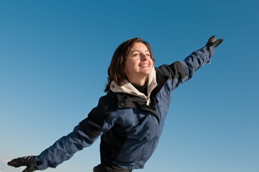 Young woman having fun on blue sky in winter time - joy and happines emotions