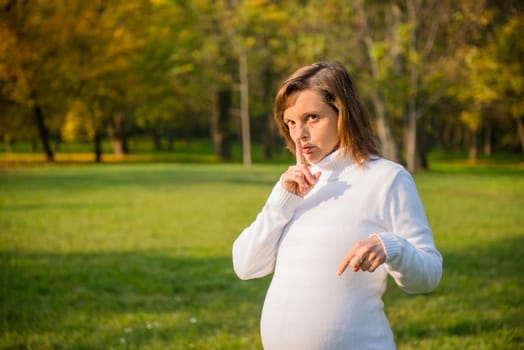 Be quite - young preagnant woman with finger on mouth