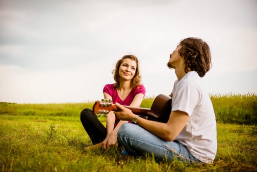 Dating couple - young man playing to his girlfriend on guitar