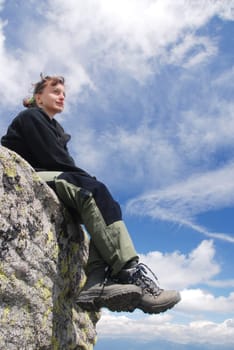 Hiking woman relaxing on rocks with blue sky