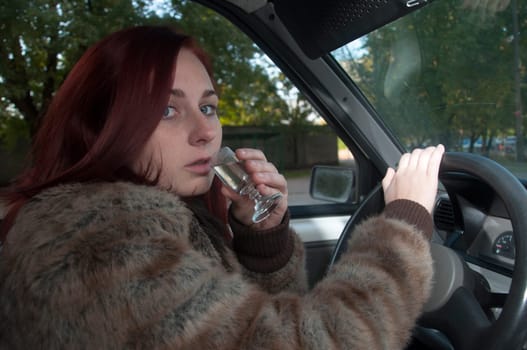 drunk woman driving the car with vodka in hand