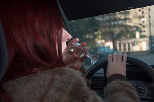 drunk woman driving car with vodka in hand