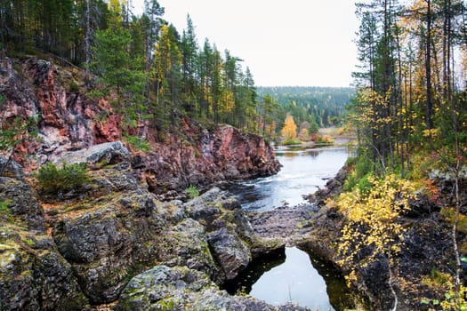 Rocku coast of river covered by autumn forest