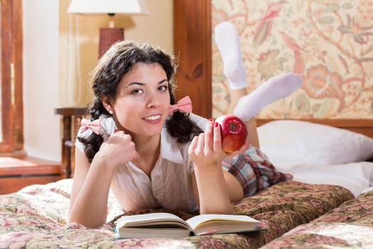 Woman in schoolgirl dress eat apple while read