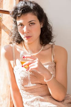 Pretty woman hold white wine glass under sunlight