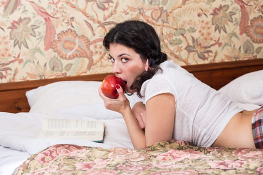 Woman in schoolgirl dress posing and eat apple