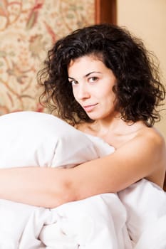 Woman under soft cover smile mysteriously at morning
