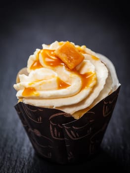 Delicious caramel cupcake on black background