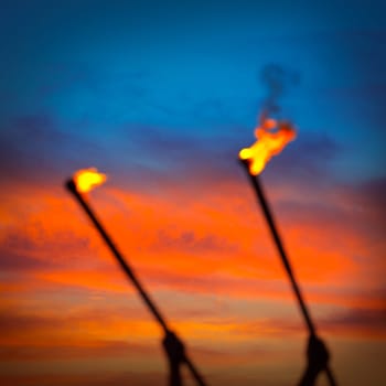 Fire torch at sunset sky with red clouds background