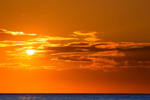Sunset orange sky background at evening over sea with clouds