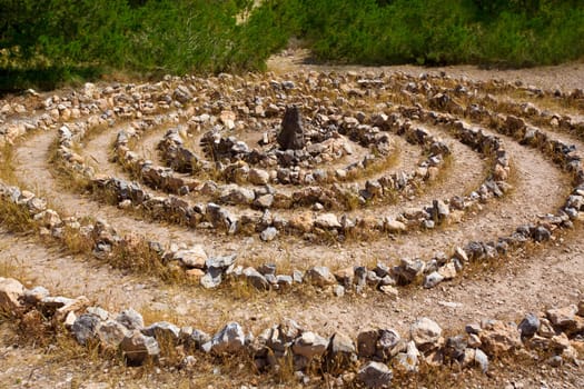 Atlantis spiral sign in Ibiza with stones on soil at Balearic Islands