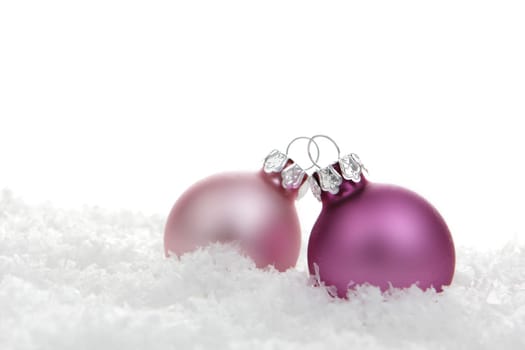 Christmas baubles pink on artificial snow with white background