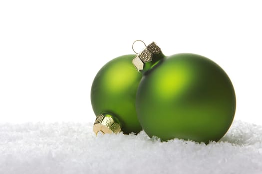 Christmas baubles green on artificial snow with white background