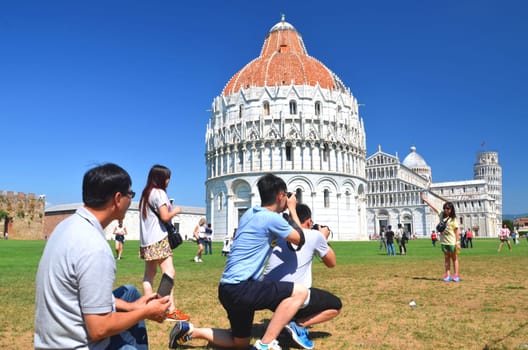 Tourists on Square of Miracles visiting Leaning Tower of Pisa, Italy.