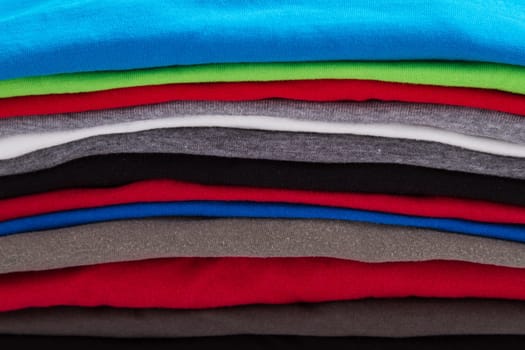 A pile of folded T shirts .