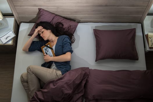 Lonely woman lying in bed missing her dead husband