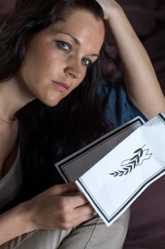 Close up portrait of young widow holding obituary