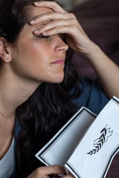 Portrait of crying young woman holding obituary