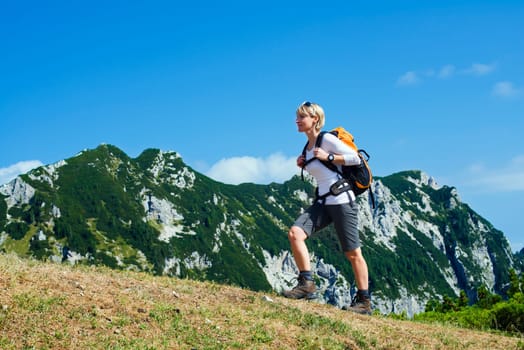 Young woman on a sunny day hiking in high mountains